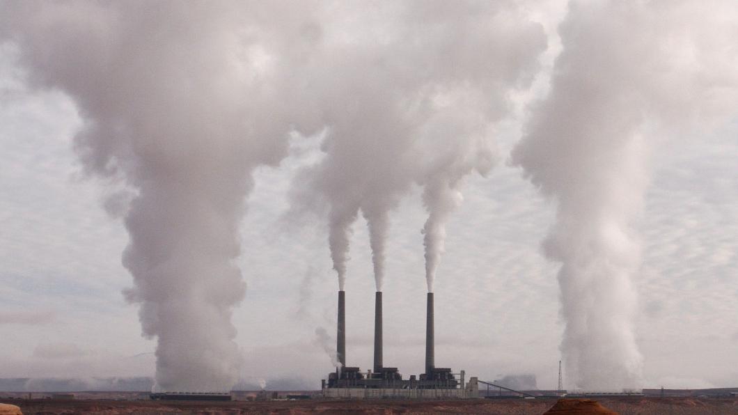 Een fabriek stoot grote witte rookpluimen uit